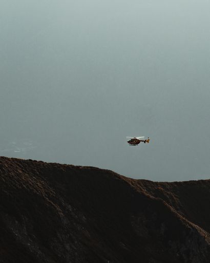 A vertical shot of a helicopter flying above the hills