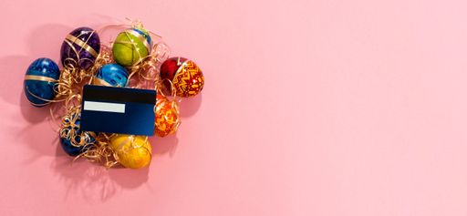 A credit card and easter eggs on pink background with space for text