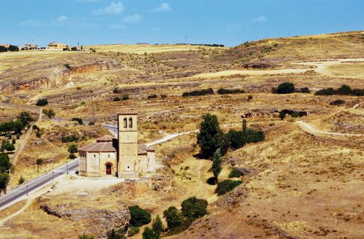 An aerial shot of a small tower next to a road in the yellow valley in Segovia, Spain