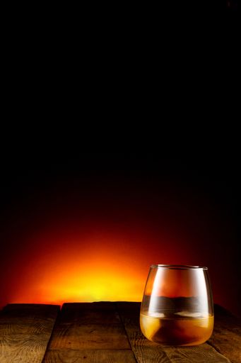 A vertical shot of a glass of whiskey isolated on a dark background