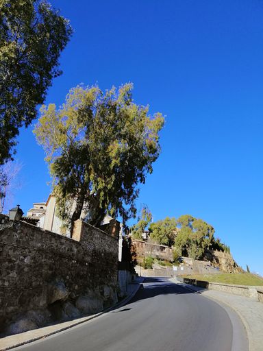 A vertical shot of a road next to houses going uphill in Toledo, Spain