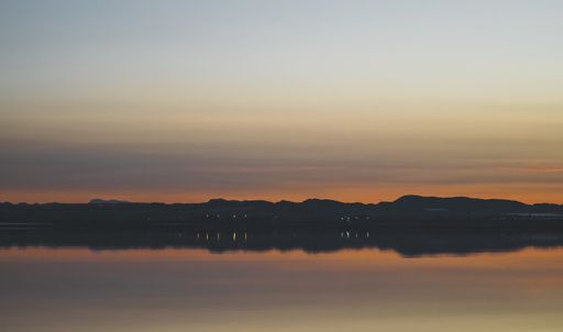 A landscape of the sea with long exposure surrounded by hills during a beautiful sunset in the evening
