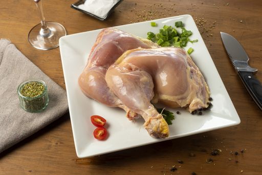 The fresh raw chicken meat on a white plate with ingredients