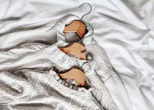 A top view of woman's vintage classic shirts with wooden hangers on the bed