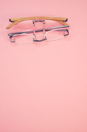 A vertical shot of glasses on a pink background with space for text