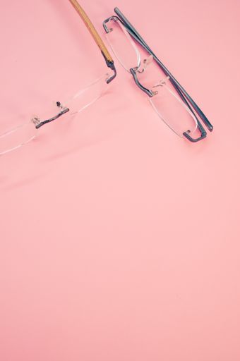 A vertical shot of glasses on a pink background with space for text