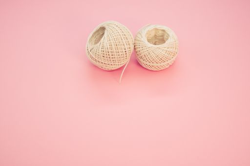 Two beige yarn balls isolated in the pink background with a copy space