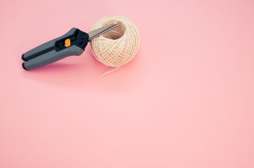 A top view of scissors on the knitting yarn isolated in the pink background with a copy space