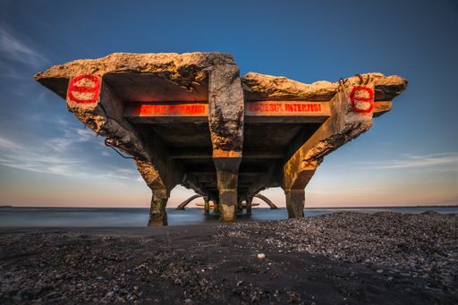An old broken bridge over the water under a blue sky