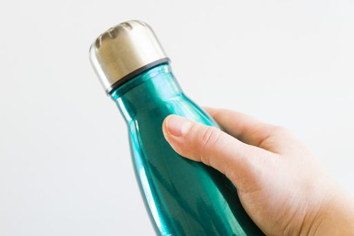 A closeup shot of ahand holding blue water thermos isolated on the white background