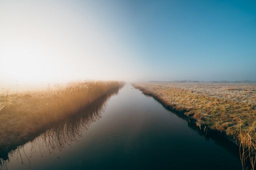 a mesmerizing shot of a reflecting river in a foggy field in Middelburg, Zeeland, The Netherlands