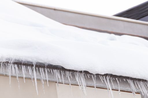 A closeup shot of snow and icicles on a roof