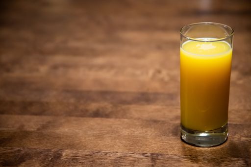 A selective focus shot of a glass of orange juice on a wooden table