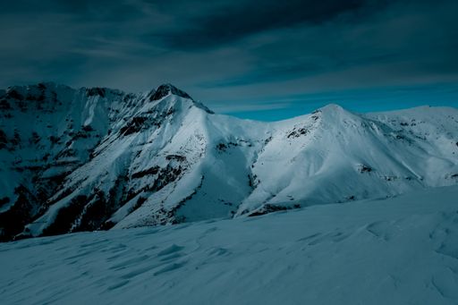 A panoramic shot on top of a snow covered mountain under cloudy skies