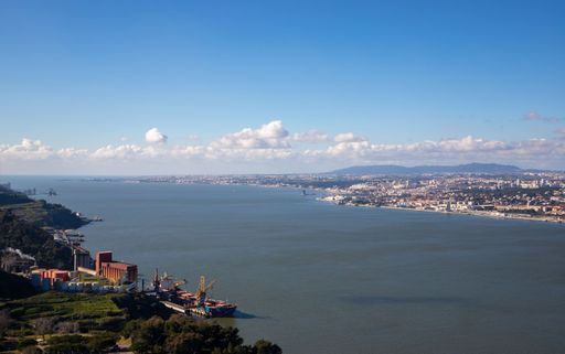 A picturesque beach landscape featuring a wide expanse of sand and a line of houses on the hill in the background