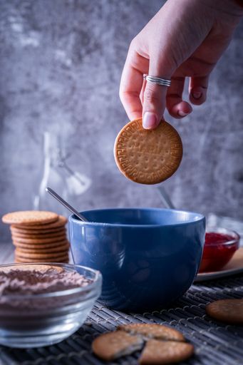 A vertical shot of a hand holding a freshly bak Maria cookie (galleta Maria)