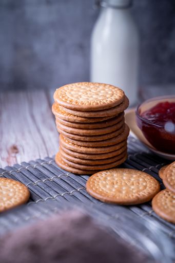 A vertical shot of fresh Maria cookies (galletas Maria) and strawberry jam