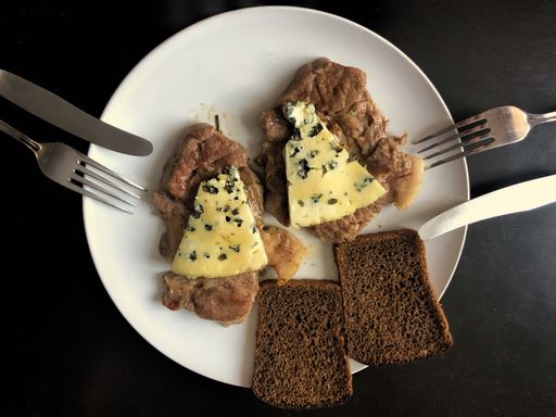 A dinner plate for two with roasted meat slices served with cheese and loaves of bread
