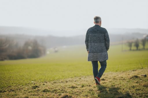 A shallow focus shot of a male walking on green park