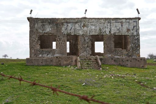abandoned houses with signs of bullets and shells on the Golan Heights, Israel and barbed wire fence