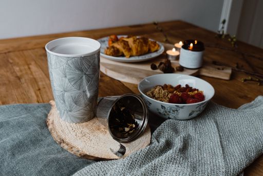 A closeup shot of a lighting candle, a cup of hot coffee and delicious pastry on a table
