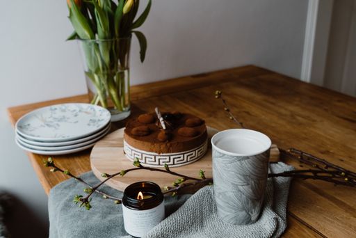 A high angle shot of tulips in a vase, a cup of espresso and a delicious chocolate cake on a table