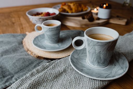 A closeup shot of a lighting candle, cups of hot coffee and delicious pastry on a table
