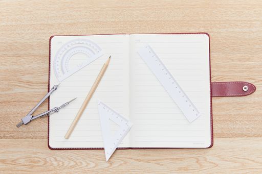 A closeup shot of a pencil, callipers, and ruler near a notebook