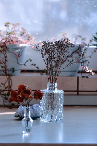 A vertical shot of a glass vase with dried roses and a vase with branches