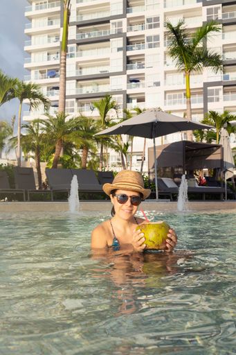 A female in sunglasses and hat relaxing and drinking a fresh coconut cocktail