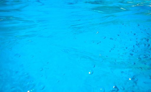 An abstract shot of a wavy, bubbly blue seawater