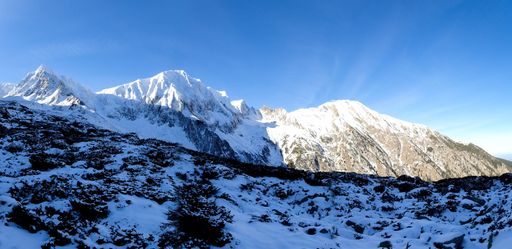 A beautiful panoramic shot of the snowy fagaras mountains in Romania with sunbeams and a blue clear sky in the background.