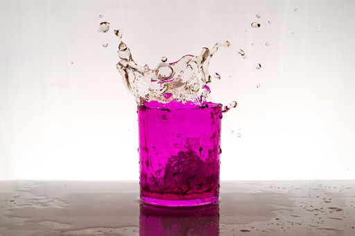 A pink iced cocktail splash on the table on a white background