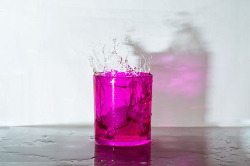 A pink iced cocktail splash on the table on a white background
