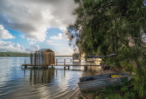 A beautiful shot of small rustic boatsheds on background of the cloudy blue sky
