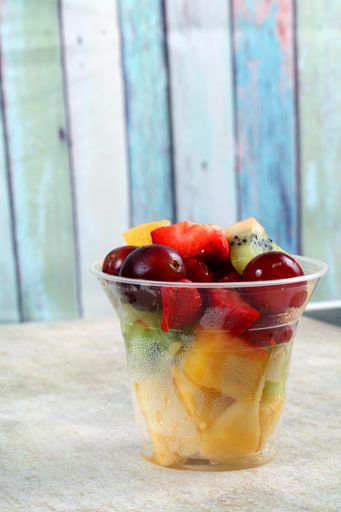 A selective focus shot of fresh fruit salad in a plastic cup