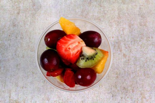 A top view of fresh fruit salad in a plastic cup