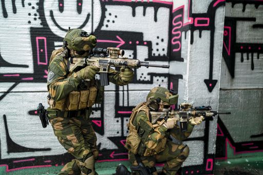 Two special force soldiers in camouflage investigating an abandoned building covered in graffiti
