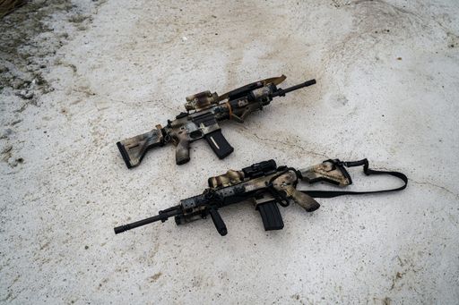 A top view of two special force rifles on the ground outdoors
