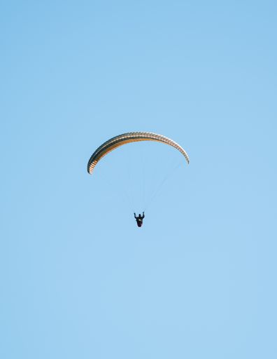 A closeup shot of a paraglider flying in a clear sky