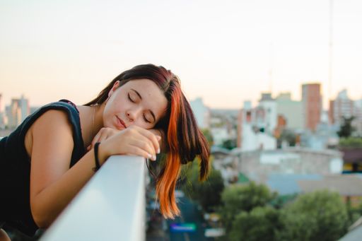 A shallow focus shot of caucasian woman with closed eyes and with city background