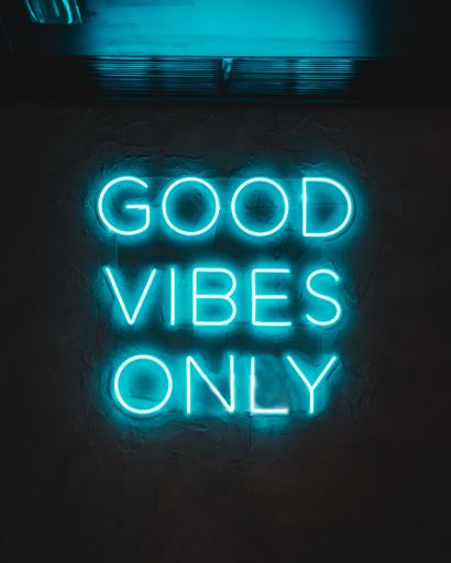 A blue neon glowing light on a wall with words ''Good Vibes Only''