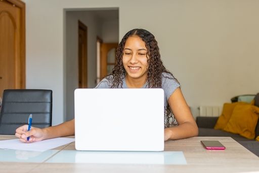 A young woman smiling at the computer camera while having a video meeting on her pc