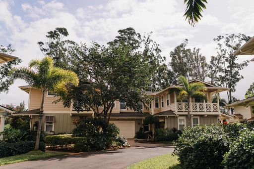A low angle shot of beautiful huge houses with green trees and cloudy sky in the background during daytime