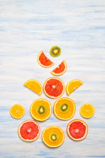 A vertical shot of tasty grapefruit, orange and kiwi slices isolated on the blue-white background