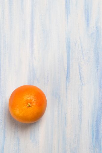 A vertical shot of an orange isolated on the blue-white background