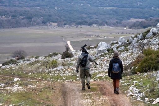 Stock photo of unrecognized friends walking in the countryside and wearing backpacks.