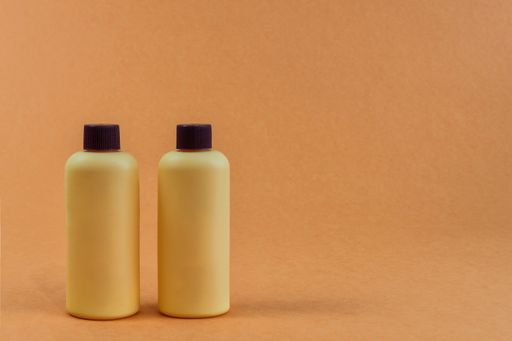 A closeup of cre colored plastic bottles isolated on an empty orange background