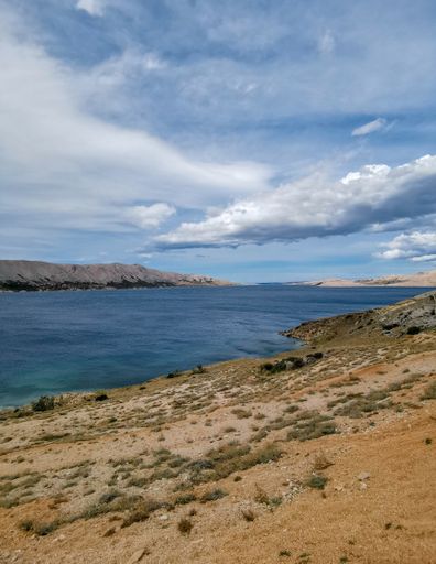 A beautiful view of the sea surrounded by rocky cliffs under a cloudy sky