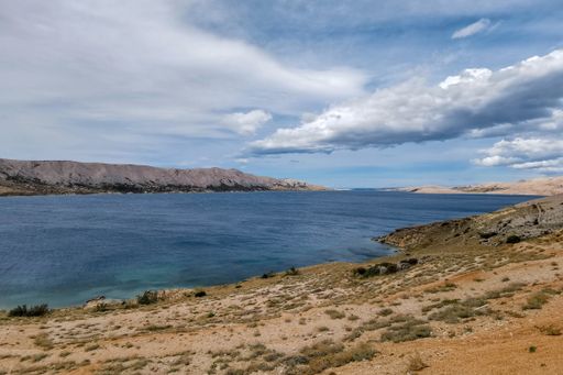 A beautiful view of the sea surrounded by rocky cliffs under a cloudy sky